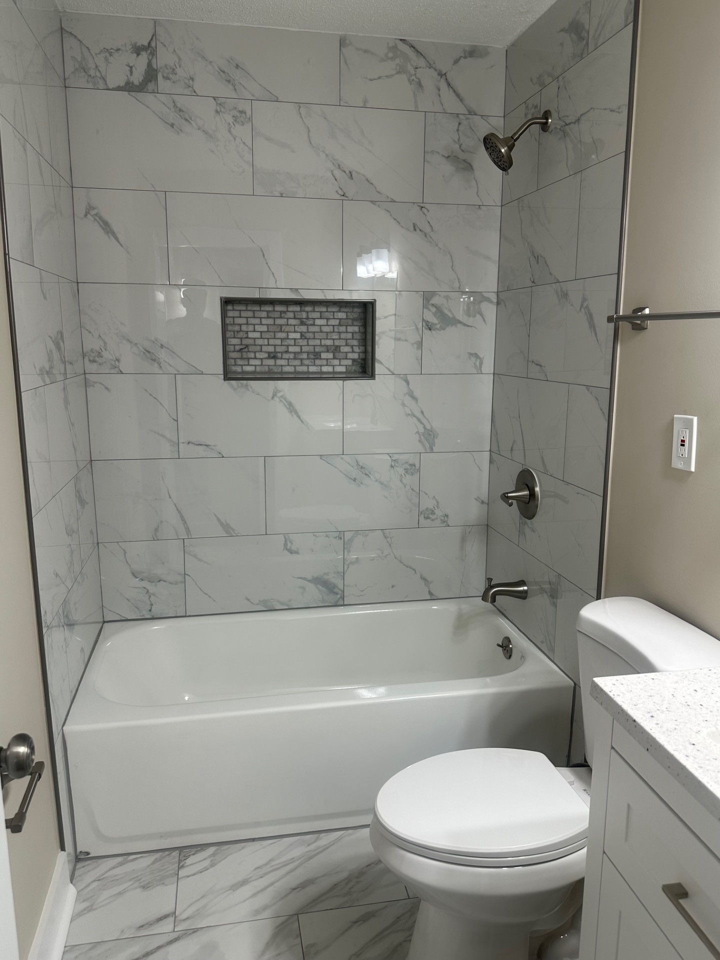 Bathroom with marble-style tile tub/shower combo and built-in niche