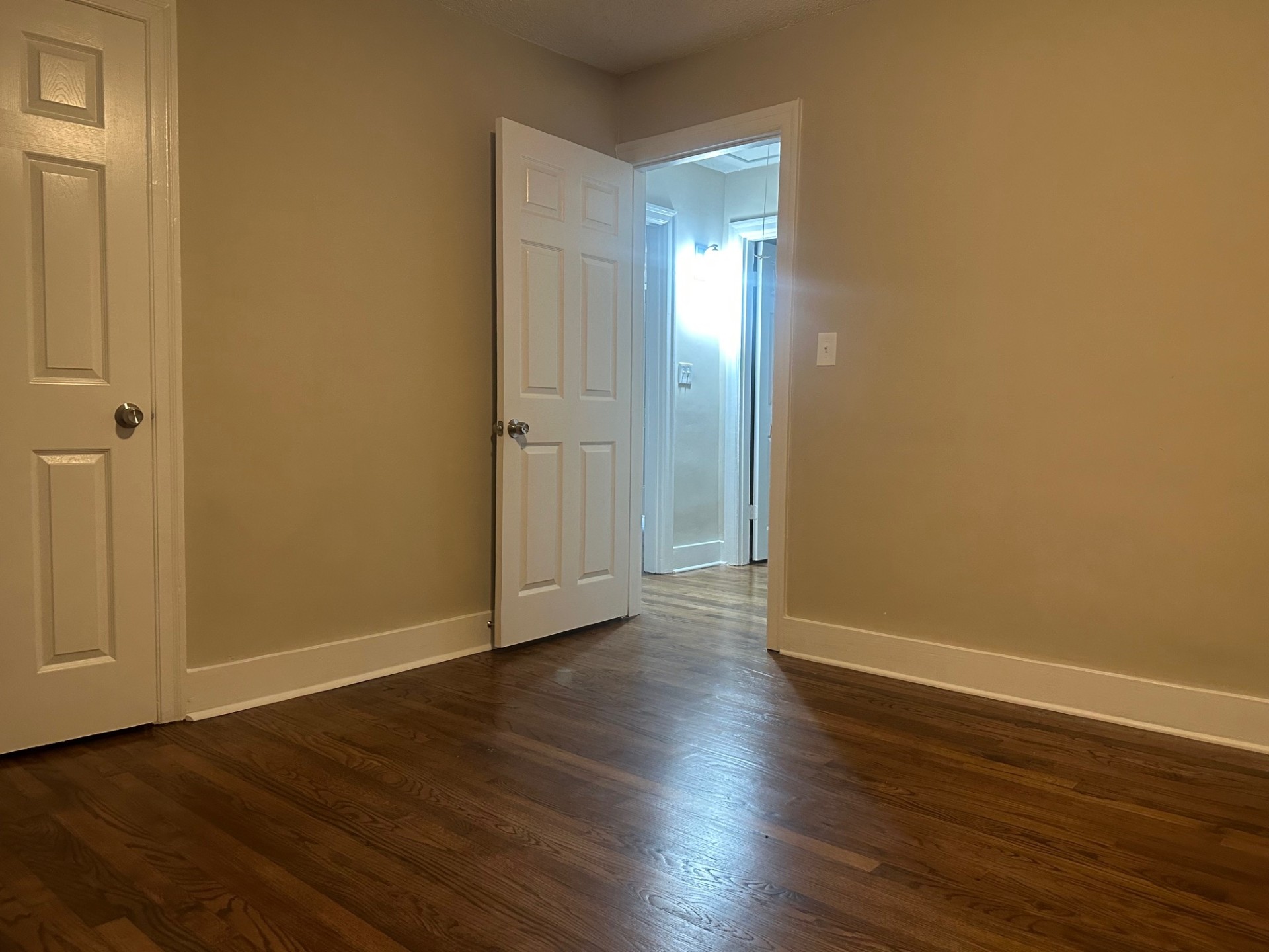 Interior bedroom with hardwood floors, two doors, and neutral paint