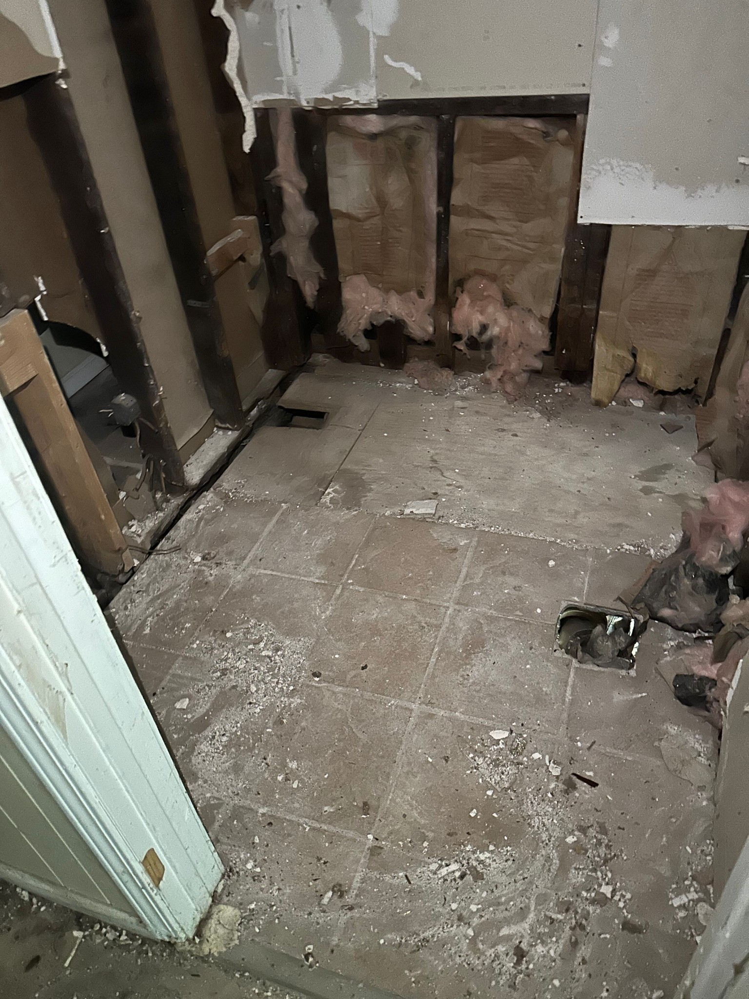 Interior room with damaged flooring and boarded window in need of rehab