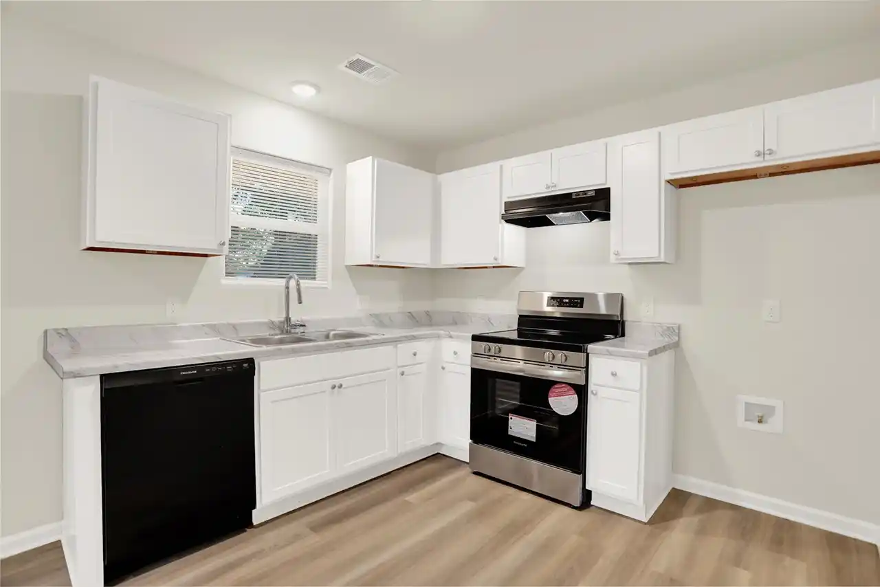 Modern kitchen with white cabinets, dishwasher, and stove in Memphis home for sale