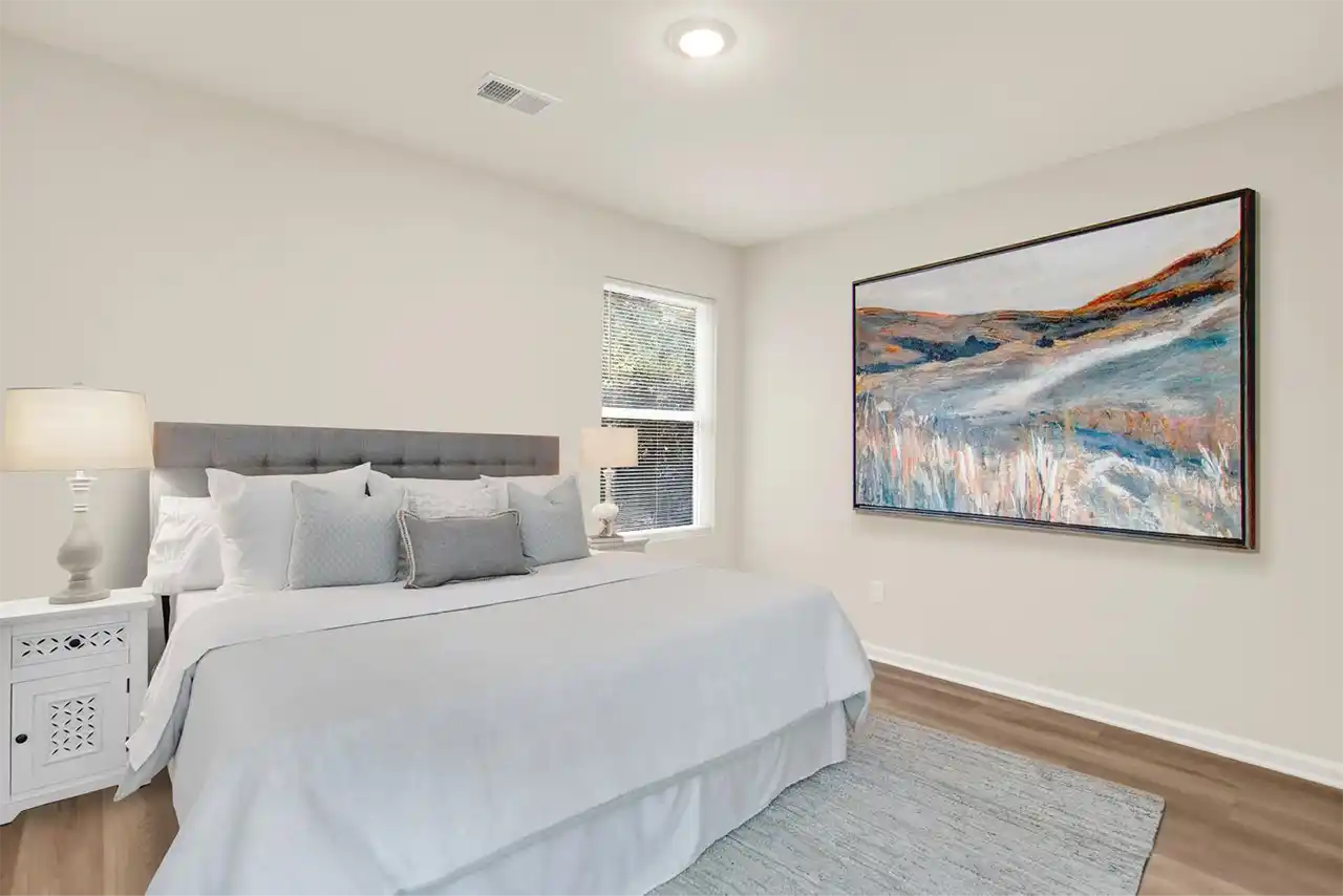 Primary bedroom with natural lighting, bed, and modern décor in staged setup