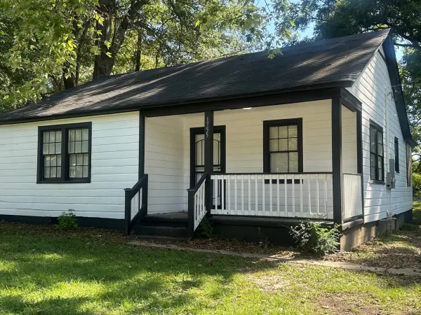 Front exterior view of renovated Memphis home with white siding, black trim, and covered porch