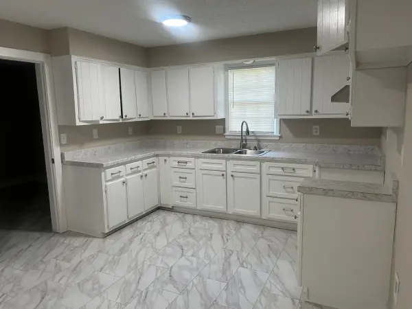 Fully renovated kitchen with white shaker cabinets, marble-style countertops, and tile flooring
