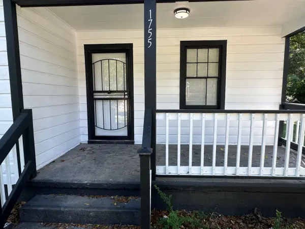 Covered front porch with storm door, porch light, and freshly painted railings