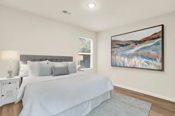 Primary bedroom with natural lighting, bed, and modern décor in staged setup